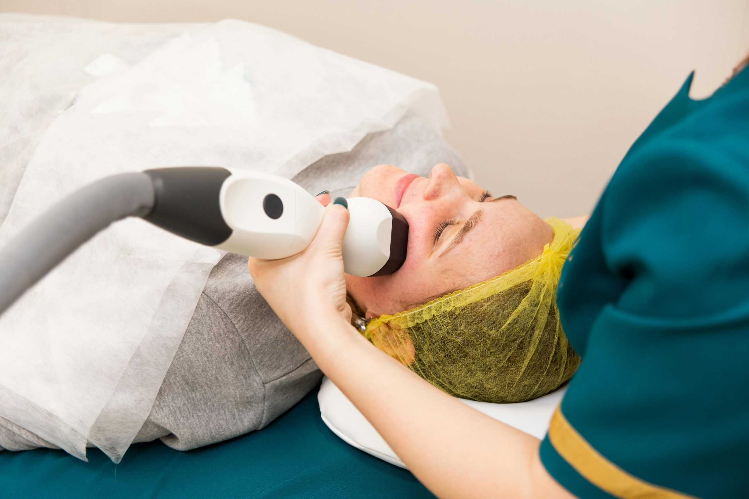 A woman receiving professional facial treatment at a clinic, highlighting beauty and technology.